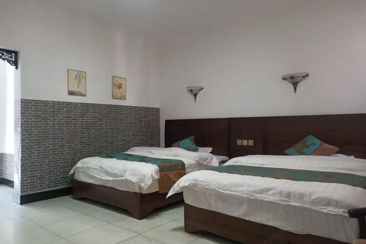 Une chambre avec deux lits, un mur décoratif en briques et des luminaires fixés au mur.