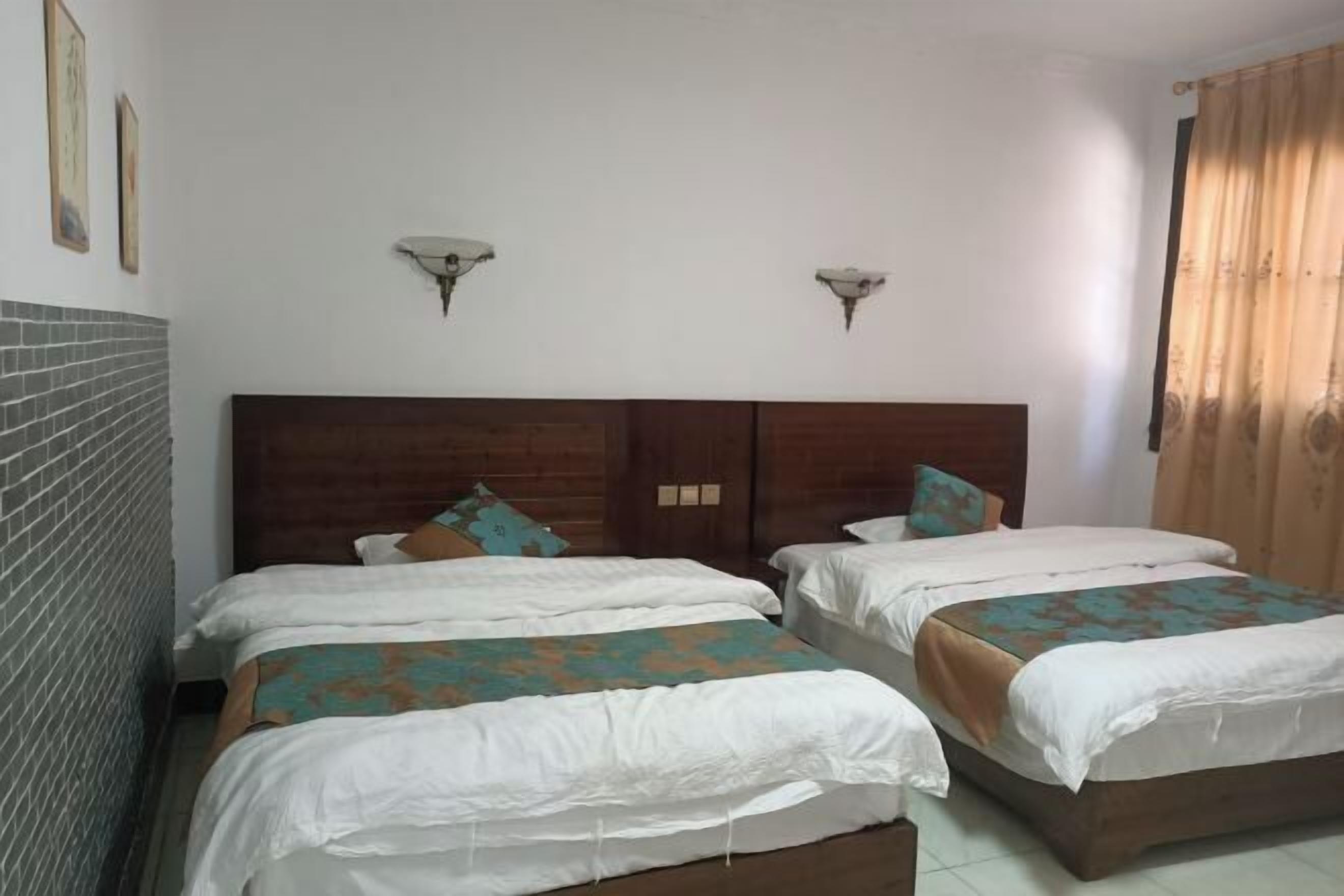 A hotel room with two beds, a brick accent wall, and a wooden headboard.