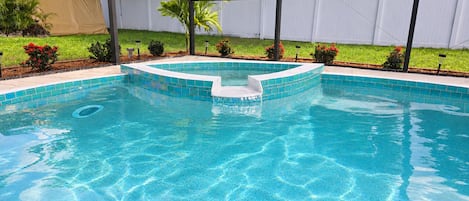 A swimming pool with a tiled edge and a small waterfall feature.