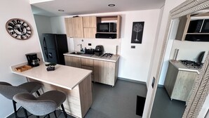 A compact kitchen with a central island, a refrigerator, a microwave, and a coffee maker. - Elegante Apartamento cerca del Tesoro y Provenza by Hoost 2408 (Medellín)