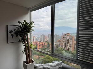 A room with a large window, a potted plant, and a world map on the wall. - Elegante Apartamento cerca del Tesoro y Provenza by Hoost 2408 (Medellín)