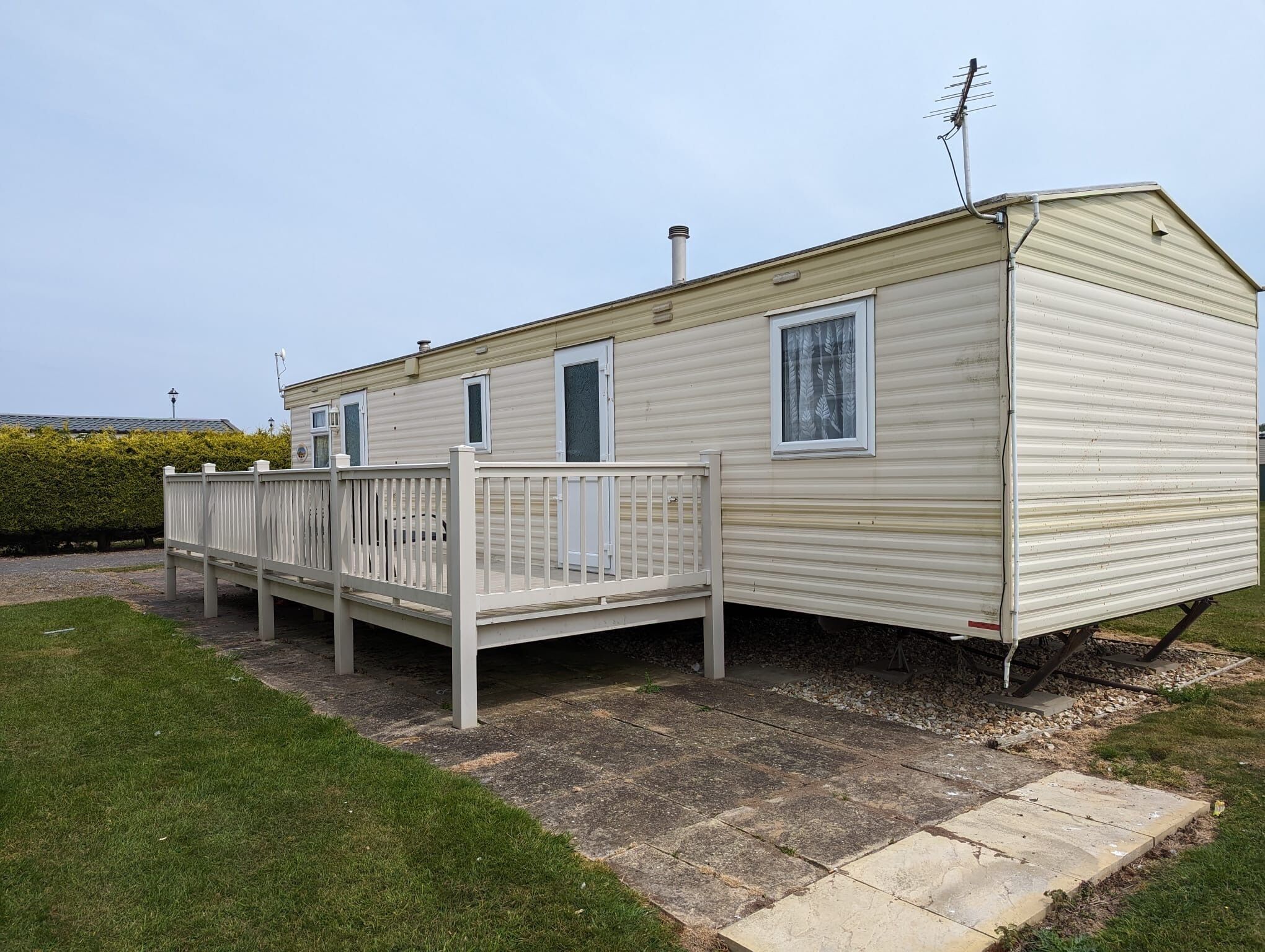A mobile home with a fenced deck and a chimney.
