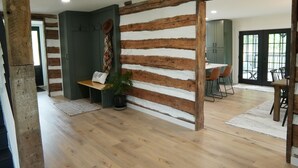Ein modernes Interieur mit einer Wand aus Holzbalken, einem Essbereich mit Stühlen und einer Bank.