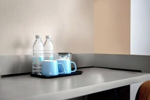 A kitchen counter with two water bottles, a coffee maker, and two blue mugs. - HanTing Harbin Museum Subway Station Hotel (HanTing Harbin Dongdazhi Street Hongbo Plaza) (Harbin)