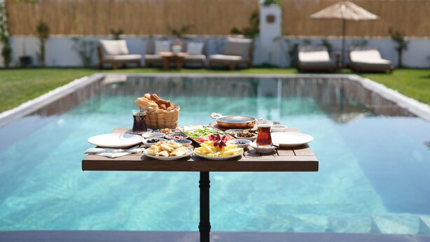 A poolside dining setup with a table, plates, and food. - Villa Egella (Dikili)