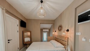 A bedroom with a wooden bed, a hanging light fixture, a mirror, and a wall-mounted TV. - Villa Egella (Dikili)