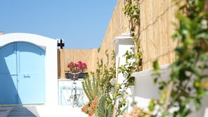 A narrow pathway leading to a blue door, with a bicycle parked nearby and a wooden fence on one side. - Villa Egella (Dikili)