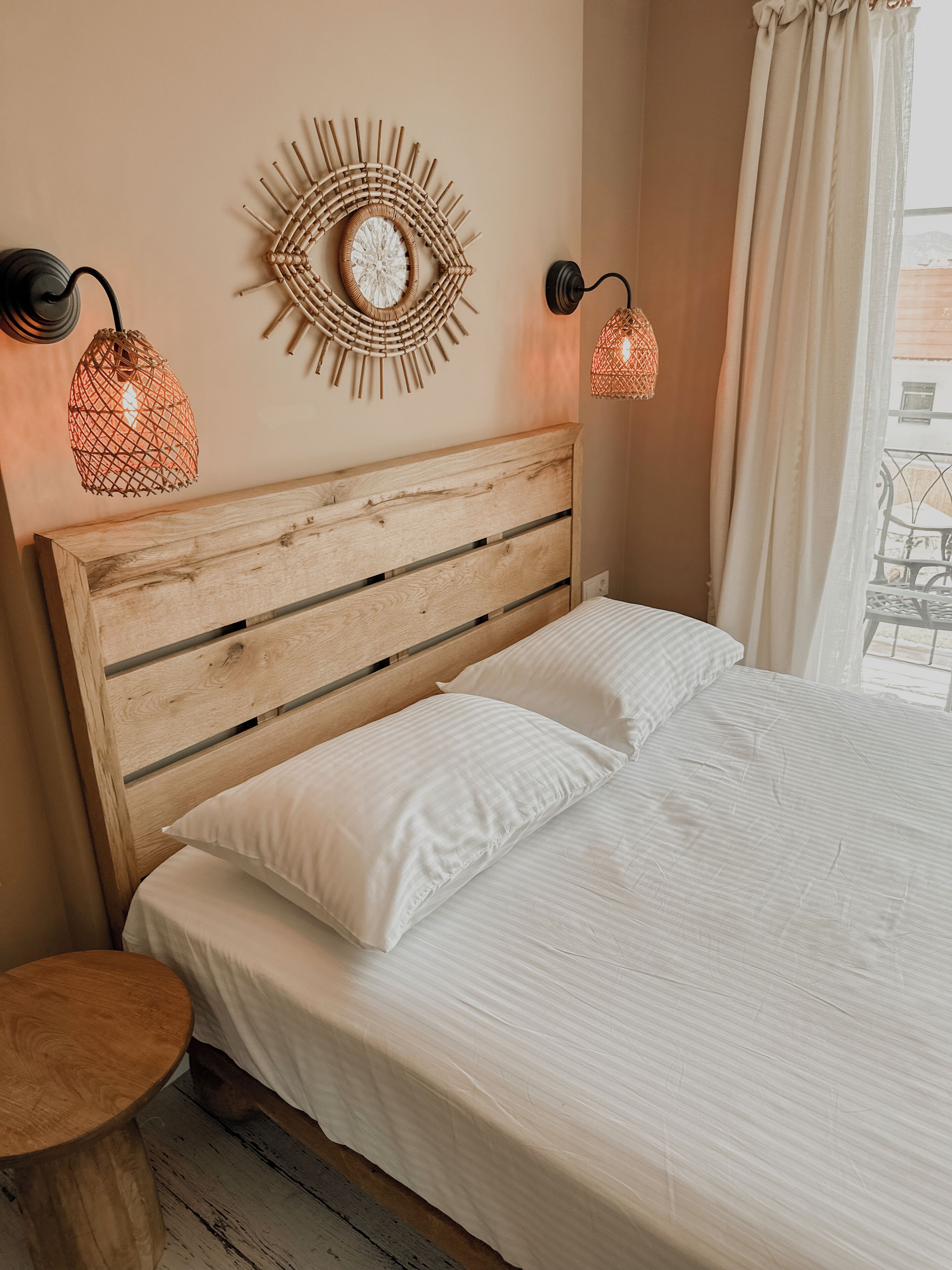 A bed with a wooden headboard, white bedding, and two wall-mounted lamps.