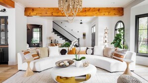 En moderne stue med en hvid sofa, et sofabord og en trappe i baggrunden.