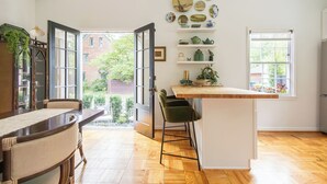 Una cocina con una mesa de madera, sillas, una barra y vistas al exterior.