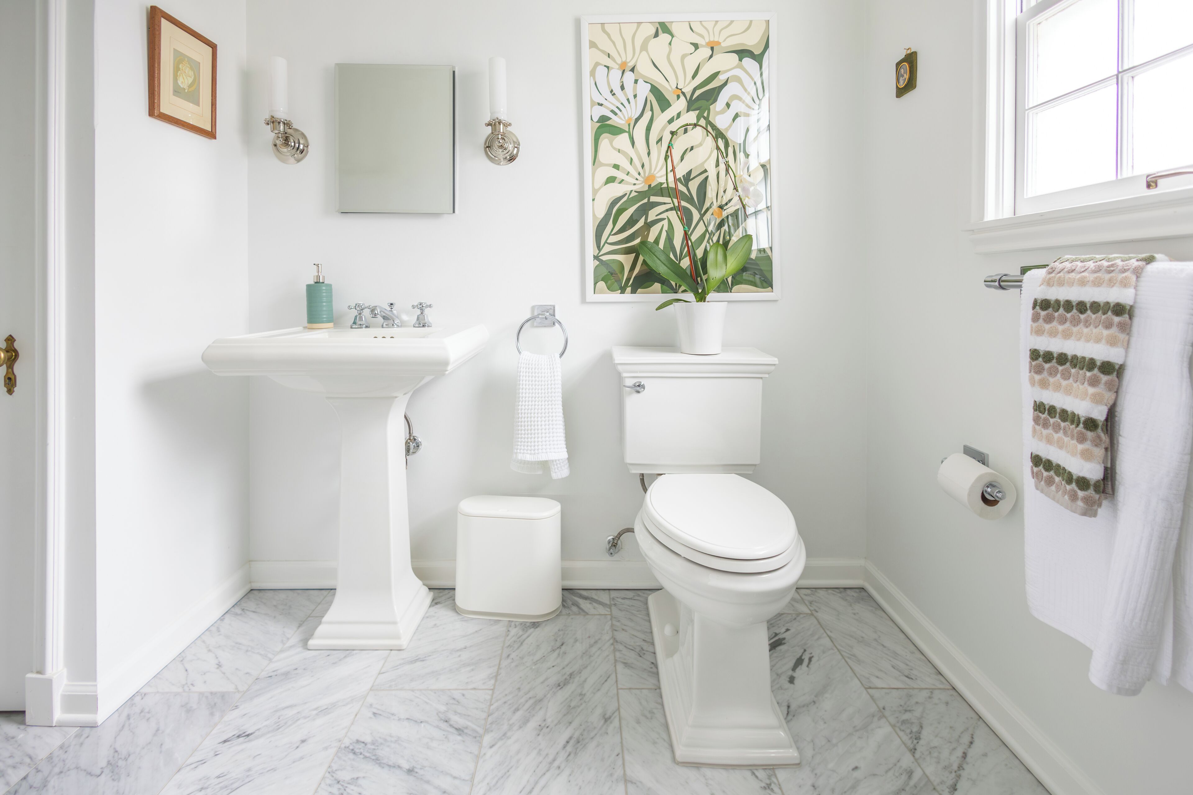 A bathroom with a pedestal sink, toilet, and a large window.