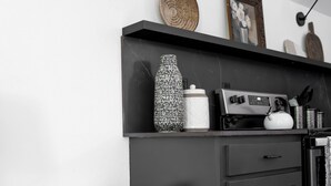 Una cocina moderna con encimera negra, una cesta de mimbre, estufa negra y una lámpara de pared.