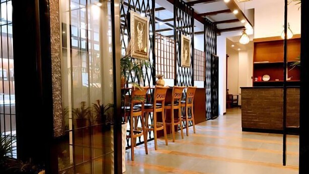 Moderni sisustus, jossa on vastaanottotiski, puutuoleja ja koristeellisilla elementeillä varustettu lasiseinä.