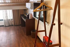 A compact room with a wooden floor, a small kitchenette, a wooden hanger stand, and a trash bin. - Zhangjiajie Jinhong Homestay (Zhangjiajie)