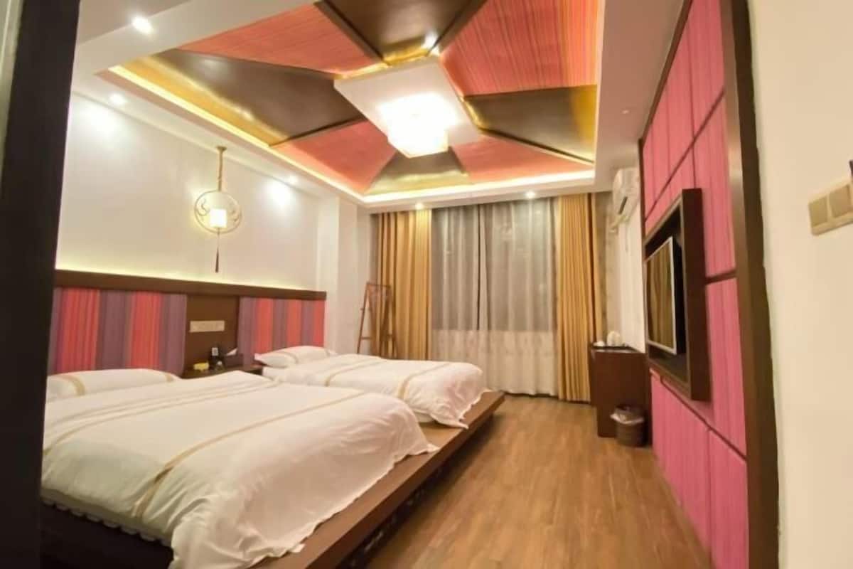 Une chambre d’hôtel avec deux lits, une télévision et un plafond orné d’un motif géométrique.