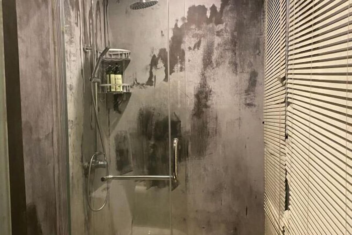 A glass-enclosed shower with a metal handle and a glass door.