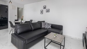 Ein modernes Wohnzimmer mit einer schwarzen Ledersofa, einem kleinen Couchtisch und Pendelleuchten.