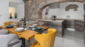 Een moderne keuken met een stenen boog, een houten eettafel en gele stoelen.