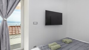 Ein modernes Hotelzimmer mit Bett, einem an der Wand befestigten Flachbildfernseher und einem Fenster mit Vorhängen.