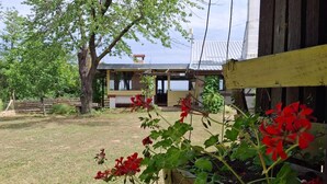 Un bâtiment rustique doté d’une terrasse en bois, entouré d’une pelouse et d’arbres.