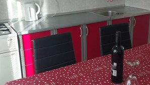 Una cocina con una decoración en rojo y blanco, una cafetera, un lavabo y una botella de vino sobre la mesa.