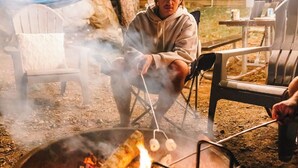 A person grilling outdoors at night with string lights overhead. - Luxury Spacious Glamping, Lake View, Grill, Pool, Pet Friendly, Swim (Delta)