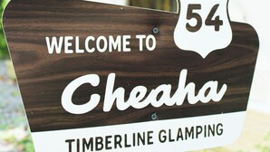Une pancarte d’accueil en bois pour Cheaha Timberline Glamping, avec un indicateur de direction.