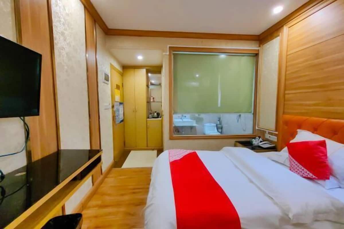 Ein Hotelzimmer mit einem Bett, einem Schreibtisch, einem Fernseher, einem Fenster und einem durch die Tür einsehbaren Badezimmer.