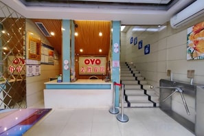A reception area with a counter, a staircase, and a wall-mounted sign.
