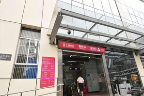 A building entrance with a sign indicating a business or service area, a staircase leading up, and a metal gate. - Guangzhou Bisheng Hotel (Hengsha Subway Station Branch) (Guangzhou)