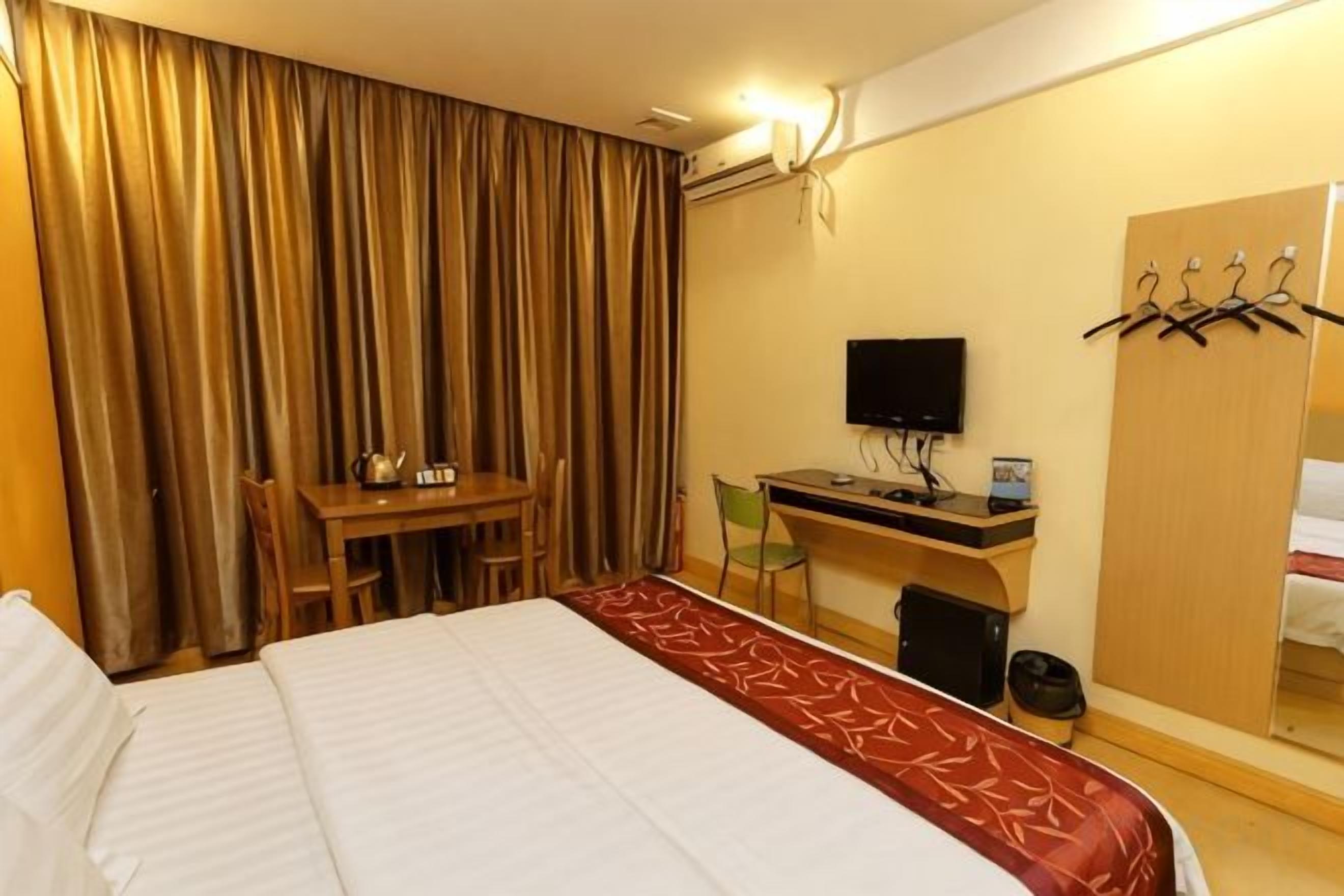 Une chambre d’hôtel comprenant un lit, un bureau avec un ordinateur, une télévision et une armoire.