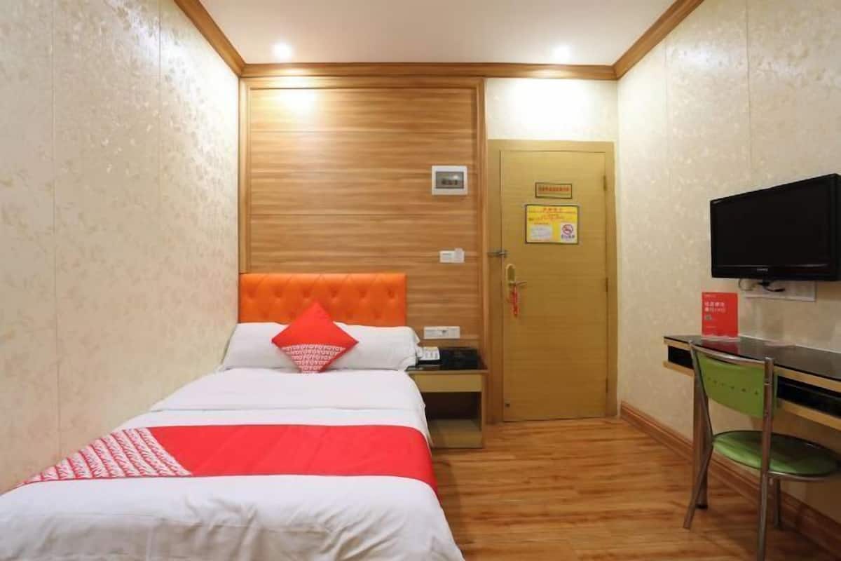 Ein Hotelzimmer mit einem Bett, einem Schreibtisch, einem Stuhl, einem Fernseher und einer Tür.