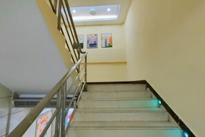 Eine Treppe mit Metallgeländer, einem Oberlicht und einer Wand mit gerahmten Bildern.