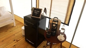 Een kleine kamer met een stapelbed, een klein zwart apparaat, een koffiezetapparaat en een welkomstbord.