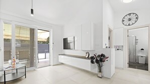 Una cocina moderna con armarios blancos, horno integrado y un amplio ventanal con persianas.