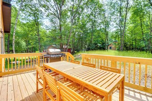 A wooden deck with a table and chairs, surrounded by trees and a grill. - Private Hot Tub: Charming Poconos Cabin! (Albrightsville)