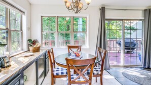 A dining area with a round table, four chairs, a chandelier, and large windows with a view of the outdoors. - Lovely McCormick Home in Savannah Lakes Village (McCormick)