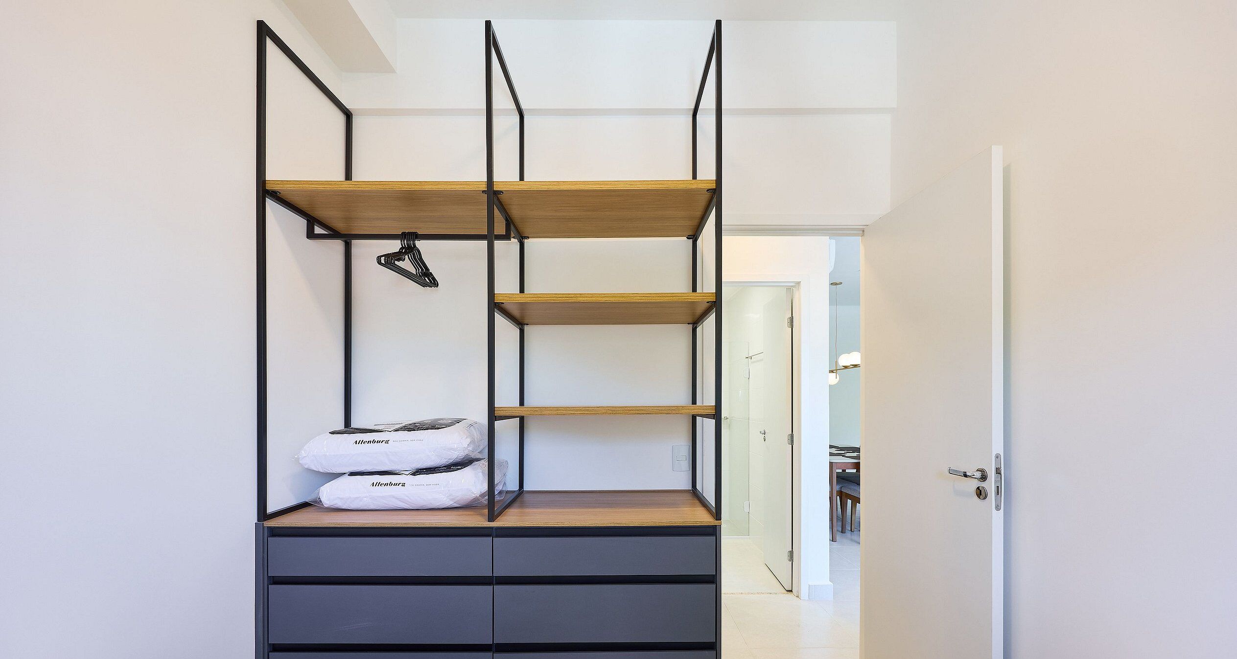 A compact room with a built-in wardrobe featuring multiple shelves and drawers.