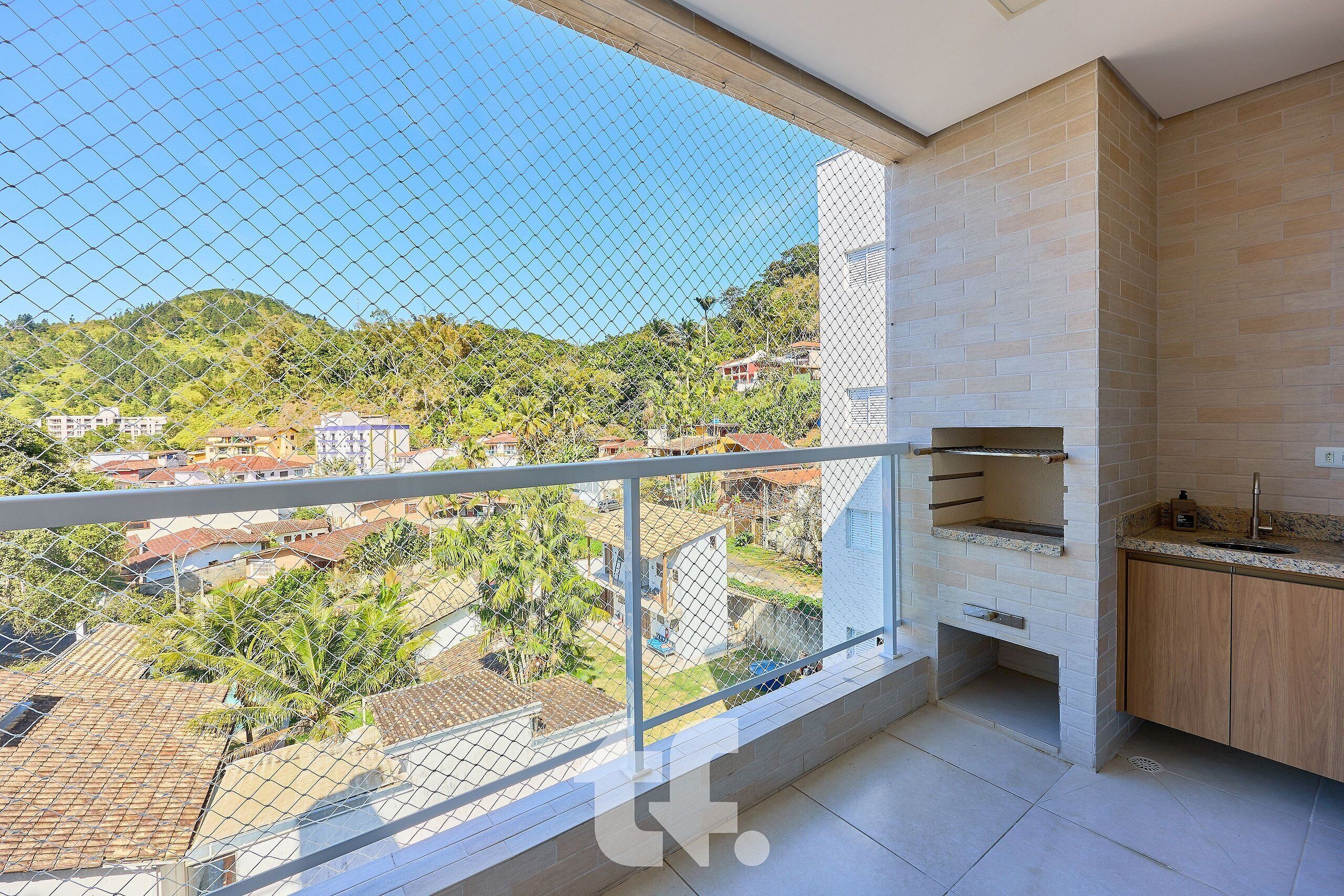 A balcony with a view of a residential area and a kitchen with a built-in grill.