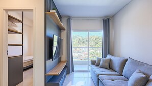 Een moderne woonkamer met een bank, televisie en een balkon met uitzicht.
