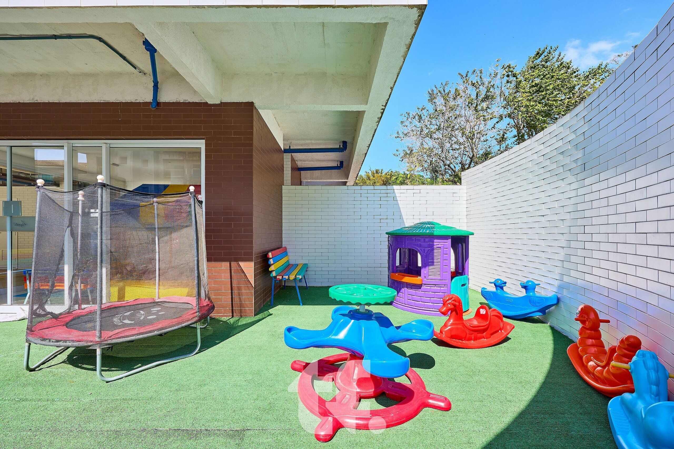 A children's play area with a trampoline, colorful play structures, and a small slide.