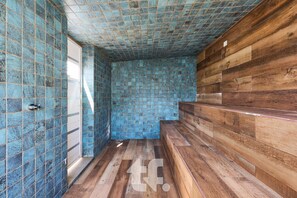 Ein Badezimmer mit blauen Mosaikfliesen, Holzboden und einer Holzbank.