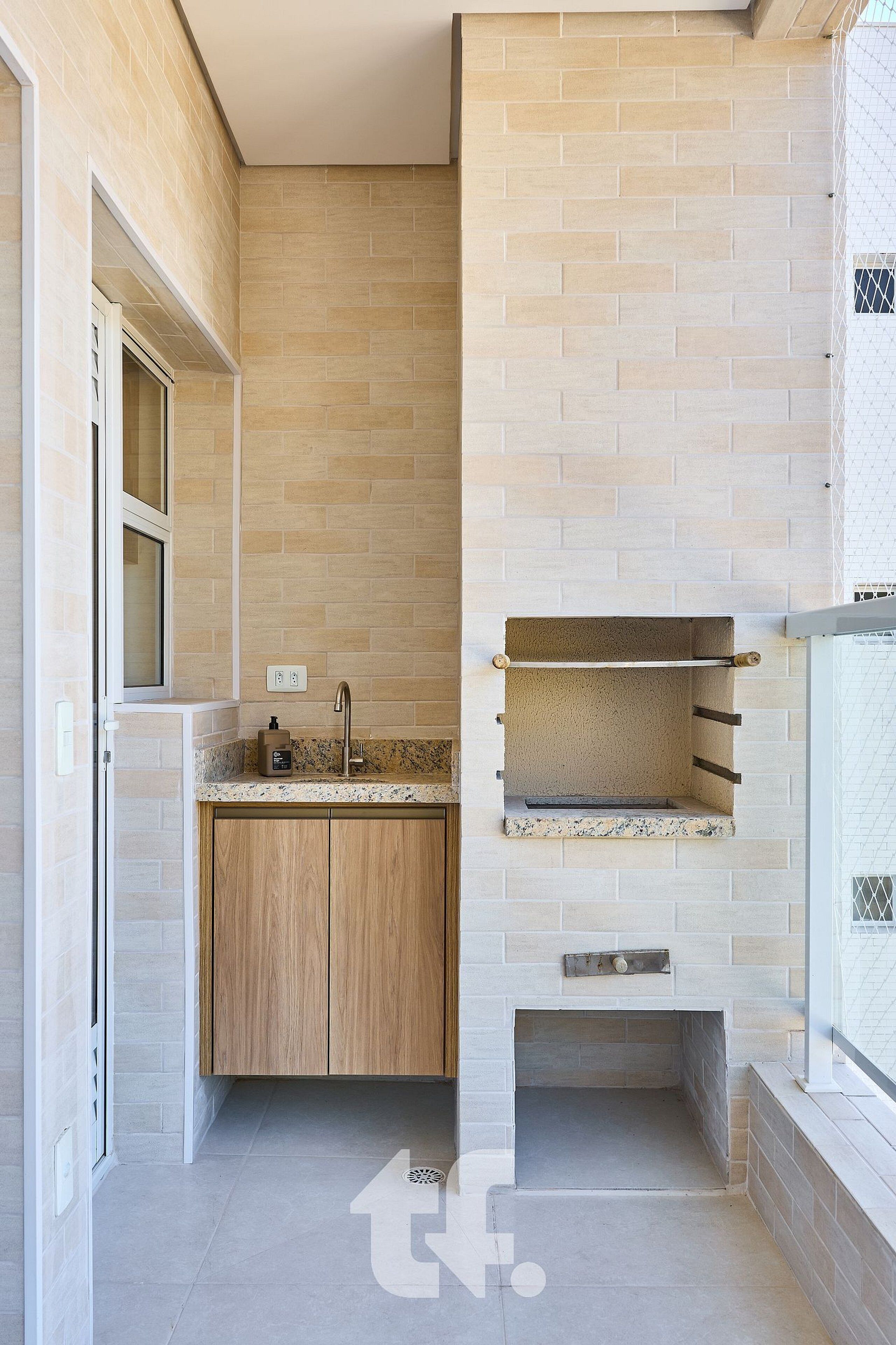 Una cocina moderna con horno empotrado, armarios de madera y una ventana sobre el lavabo.