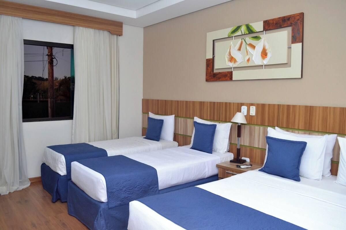 Ein Hotelzimmer mit zwei Betten, einem Nachttisch, einer Lampe und einem Bild an der Wand.