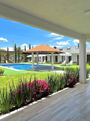 A covered outdoor area with a swimming pool, lounge chairs, and a gazebo. - Hotel El Jaguar (Teotihuacan)