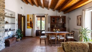 Un interior rústico con techo de madera, una mesa de comedor con sillas, una estantería y una planta en maceta.