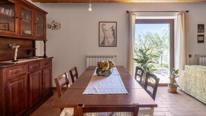 Comedor con mesa de madera, sillas, un aparador y un florero con flores.