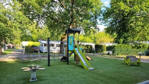 Ein Spielplatz mit Rutsche, Klettergerüsten und Schaukelpferd.