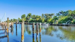A calm waterway with wooden pilings, a boat docked on the right, and lush greenery in the background. - Modern 1-bedroom apartment, Walk to Las Olas Blvd and Beach, Free parking (Fort Lauderdale)