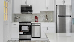 A modern kitchen with white cabinets, stainless steel appliances, and a marble countertop. - Modern 1-bedroom apartment, Walk to Las Olas Blvd and Beach, Free parking (Fort Lauderdale)